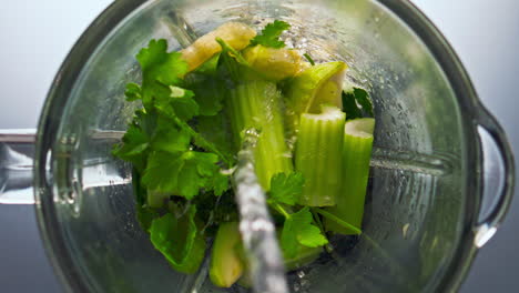 Fresh-liquid-pouring-blender-with-vegetables-for-smoothie-top-view-close-up