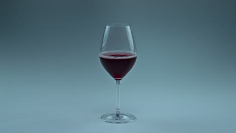 Closeup-red-wine-drop-falling-glass.-Rose-tipple-splashing-inside-clean-goblet