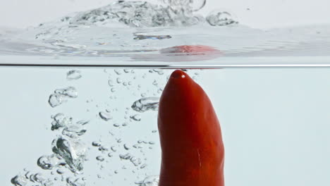 Red-pepper-splashing-liquid-surface-closeup.-Fresh-spicy-vegetable-wash-bouncing