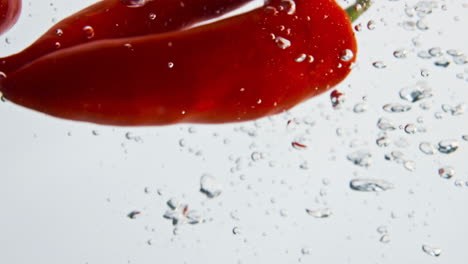Red-peppers-splashing-liquid-closeup.-Beautiful-spicy-vegetables-fall-bubbling