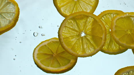 Nahaufnahme-Frischer-Zitronen-Unter-Wasser-Auf-Weißem-Hintergrund.-Schwimmende-Zitrusscheiben.