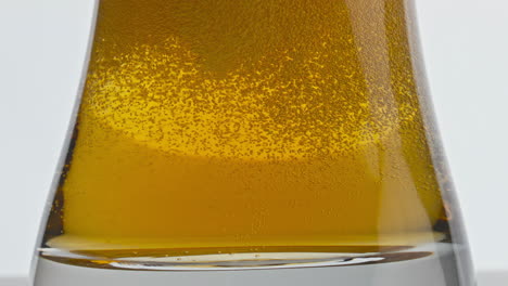 Craft-iced-beer-fizzing-glass-bottom-closeup.-Pasteurized-barley-lager-bubbling