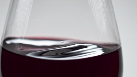 Merlot-wine-lightly-shaking-glass-closeup.-Grape-rose-beverage-surface-waving