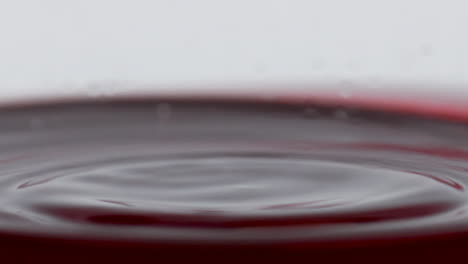 Blob-splashing-inside-wine-glass-closeup.-Drop-falling-slow-inebriant-beverage