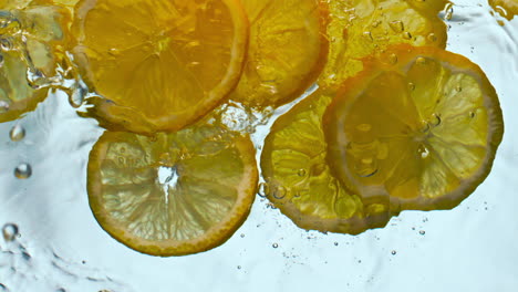 Orangenstücke,-Die-In-Flüssigkeit-Spritzen,-Nahaufnahme.-Zitrusfruchtscheiben,-Die-Unter-Wasser-Schwimmen