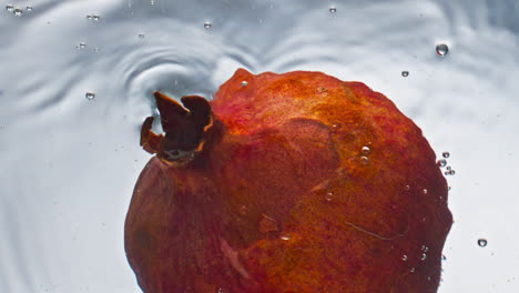Closeup-pomegranate-flowing-water-in-light-background.-Sweet-tropical-fruit