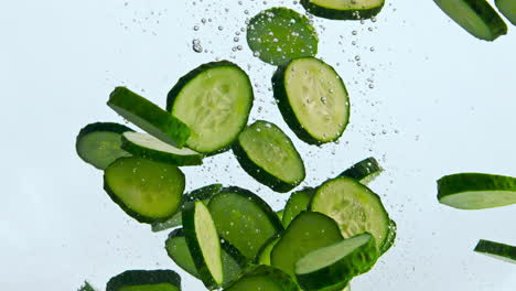 Slices-green-cucumber-floating-in-water-close-up.-Vegetable-raising-up-in-liquid