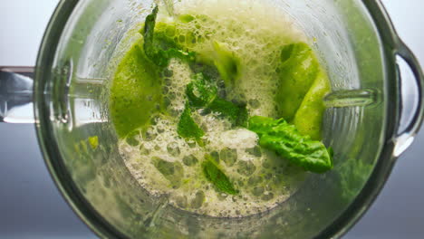 Mixing-vegetable-cocktail-blender-close-up-top-view.-Veggies-herbs-blending.