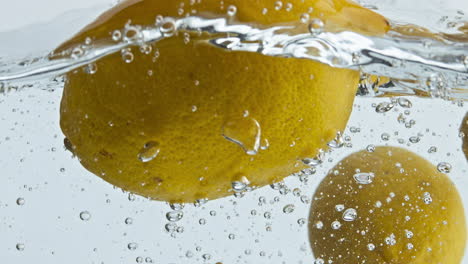 Tropische-Zitronen,-Die-Im-Wasser-Spritzen,-Nahaufnahme.-Gelbe,-Saure-Früchte,-Die-Transparent-Hüpfen