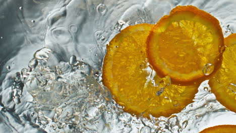 Orangenstücke-Fallen-Auf-Die-Wasseroberfläche,-Nahaufnahme.-Leckere-Süße-Fruchtscheiben-Planschen