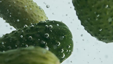 Closeup-cucumbers-falling-liquid-in-light-background.-Garden-vegetables-floating