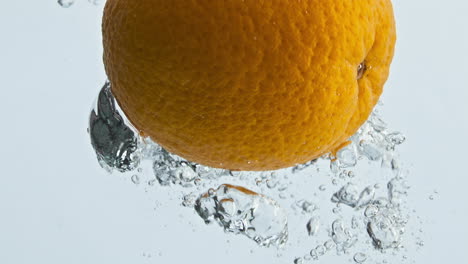 Fresh-orange-splashing-water-in-light-background-closeup.-Tropical-fruit-bounce