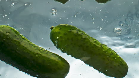 Nahaufnahme-Bio-Gurken-Im-Wasser-Schwimmen-Auf-Hellem-Hintergrund.-Frisches-Grünes-Gemüse