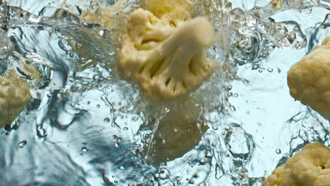 Fresh-cauliflower-pieces-falling-water-close-up.-Organic-cabbage-making-splashes