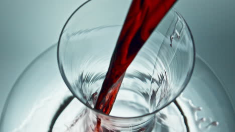Pouring-red-liquid-glassware-closeup.-Seasoned-alcoholic-drink-jet-flowing-down