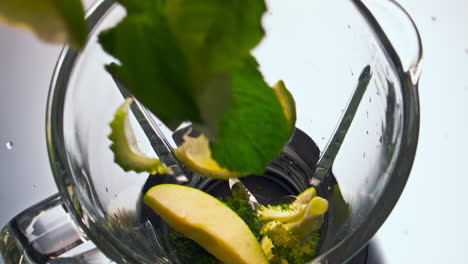 Fresh-vegetables-falling-blender-bowl-to-make-delicious-healthy-drink-close-up.
