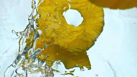 Gelbe-Ananasscheiben,-Die-Ins-Wasser-Spritzen,-Nahaufnahme.-Saftige-Ananas-Fallen-In-Die-Flüssigkeit