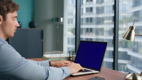 Pensive-manager-typing-mockup-laptop-keyboard.-Businessman-watching-blue-screen