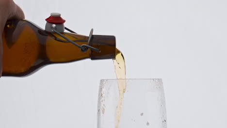 Man-hand-pouring-beer-from-bottle-to-glass-in-super-slow-motion-close-up.