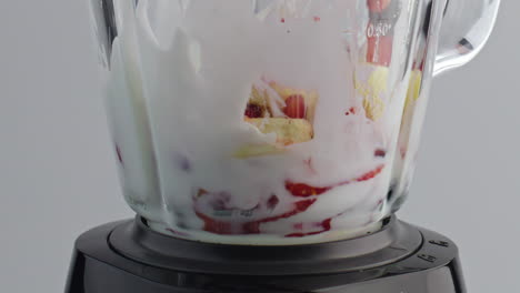 Fruits-add-milk-blender-close-up.-Natural-ingredients-falling-dairy-liquid.