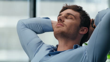 Closeup-man-relaxing-dreaming-at-office.-Calm-director-stretching-body-workplace