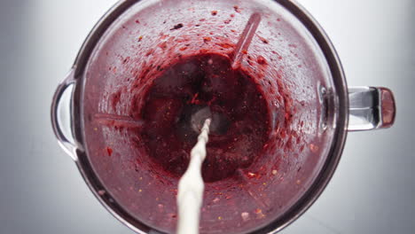 Closeup-milk-pouring-blender-with-berry-blend-in-super-slow-motion-top-view.