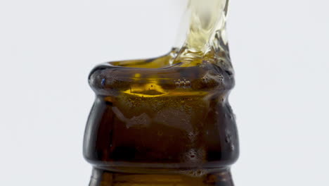 Stream-light-beer-splashing-from-bottle-neck-in-super-slow-motion-close-up.