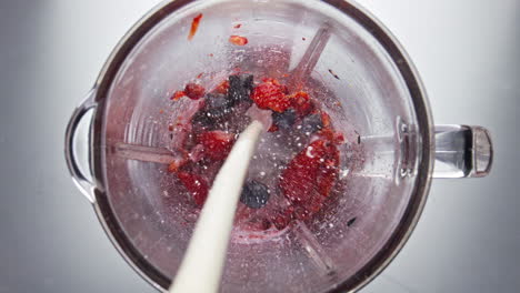 Fresh-milk-pouring-blender-bowl-with-ripe-berries-in-super-slow-motion-close-up.
