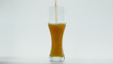 Stream-lager-beer-flowing-into-glass-at-white-background-close-up.-Golden-liquid