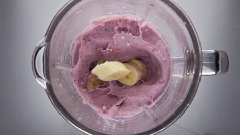 Banana-falling-berry-smoothie-in-blender-close-up.-Natural-ingredients-for-drink