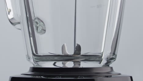 Closeup-blender-blades-spinning-inside-empty-glass-bowl-in-super-slow-motion.