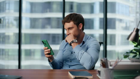 Laughing-boss-reading-smartphone-message-office.-Man-smiling-looking-cellphone