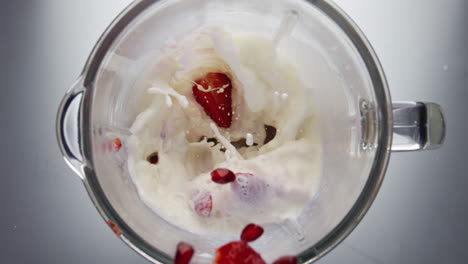 Berries-falling-blending-milk-in-mixer-close-up.-Strawberry-blueberry-mixing.