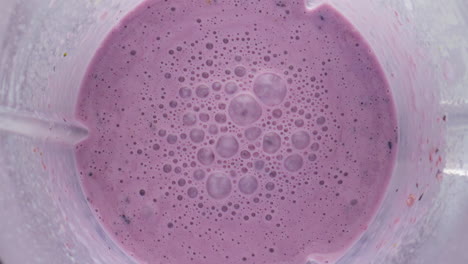 Mixed-berry-smoothie-blender-bowl-close-up-top-view.-Organic-milkshake-preparing