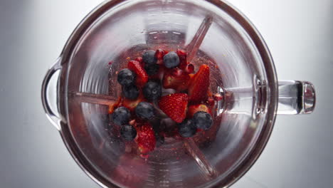 Fresh-ripe-berries-blending-in-mixer-close-up.-Top-view-preparing-smoothie.