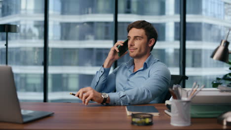 Handsome-businessman-picking-up-smartphone-at-workplace.-Man-answering-call