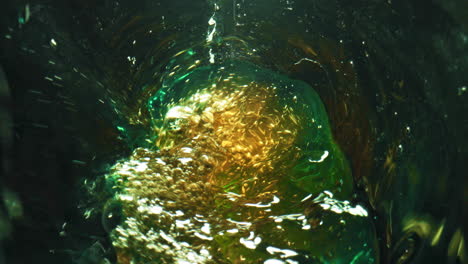 Bottle-swirling-craft-beer-closeup.-Lager-stream-making-foam-in-green-glass