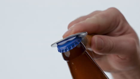 Beer-opening-bottle-opener-hold-by-unknown-man-at-white-background-close-up