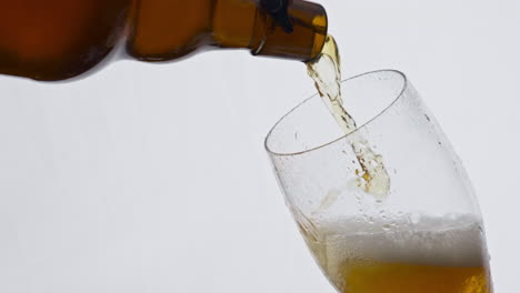 Fresh-beer-spilling-bottle-to-glass-in-super-slow-motion-closeup.-Lager-beverage