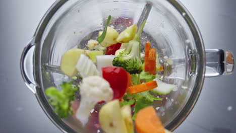 Vitamin-vegetables-dropped-blender-in-with-spinning-blades-close-up-top-view.