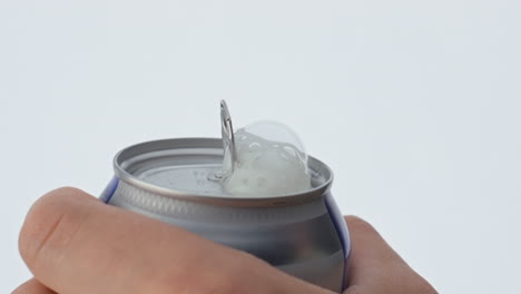 Closeup-man-hand-open-can-of-beer-in-super-slow-motion.-Bubbling-foam-spilling.