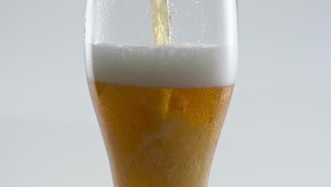 Cerveza-De-Primer-Plano-Vertiendo-Vidrio-Haciendo-Una-Sabrosa-Espuma-Densa-Sobre-Fondo-Blanco.