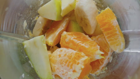Top-view-chopping-blender-full-juicy-fruits-close-up.-Vegetarian-smoothie.