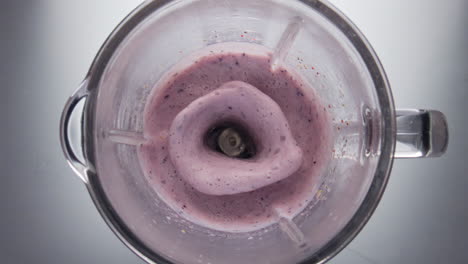 Closeup-berry-cocktail-mixing-in-blender-bowl-super-slow-motion-top-view.