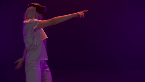 Joyful-girl-dancing-augmented-reality-headset-in-neon-lights.-Happy-gamer-play
