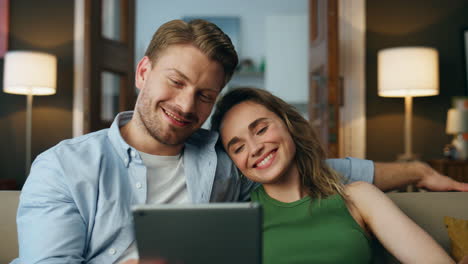 Happy-couple-make-videocall-tablet-at-home-zoom-on.-Romantic-family-waving-hands