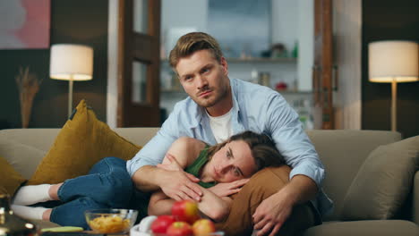 Sad-spouses-watching-movie-evening-living-room.-Calm-focused-man-caressing-wife