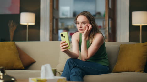 Sad-lady-using-smartphone-home-sofa.-Depressed-woman-talking-video-chat-indoors