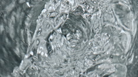 Water-swirling-transparent-glass-top-view.-Liquid-vortex-with-bubbles-closeup