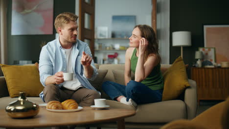 Chilling-spouses-drinking-tea-at-sofa-interior.-Couple-enjoying-coffee-talking